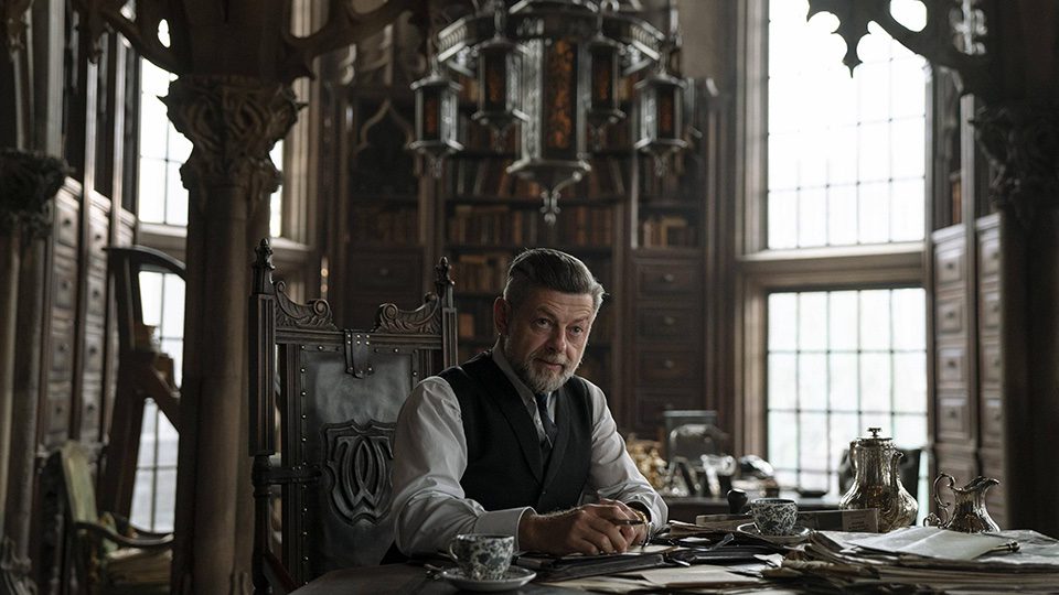 Andy Serkis as Alfred in The Batman, sitting at a desk in an opulent office