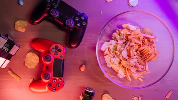 Table top with two game controllers and a bowl of chips