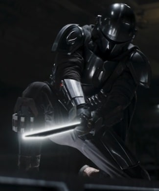 The Mandalorian Din Djarin in a kneeling position appearing to struggle holding up the Darksaber