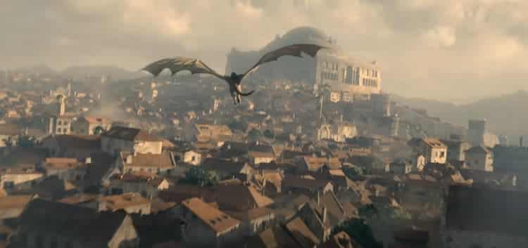 A daytime vista of the city of King's Landing with a dragon flying overhead.