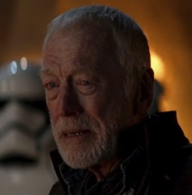 Close up of Max von Sydow as Lor San Tekka from Star Wars: The Force Awakens with stormtroopers and a burning fire behind him.