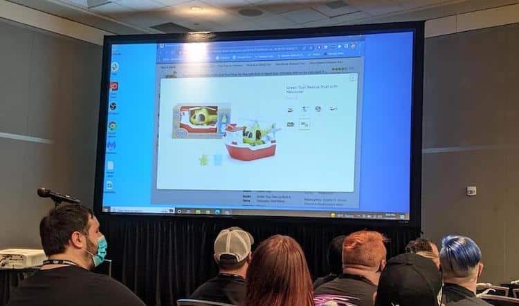 Large display panel in one of the RTX panel rooms projecting a computer desktop with a web browser open. The browser shows the image of a toy, which is a boat carrying a helicopter. 
