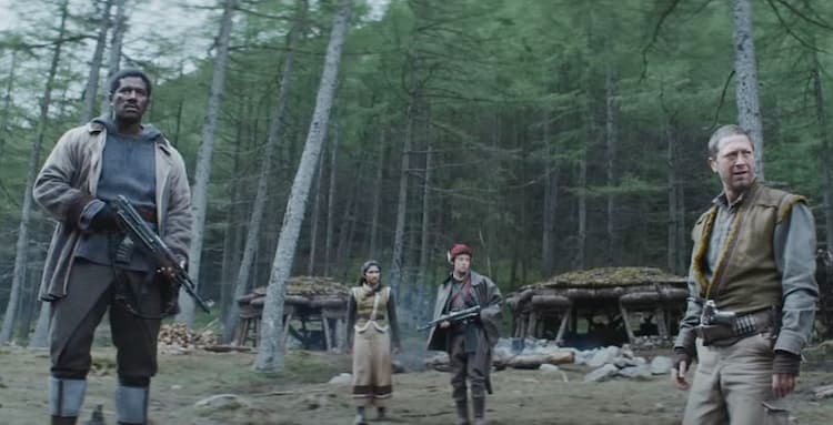 A group of four rebels standing with a primitive campsite behind them, looking warily at something.