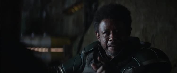 Saw Gerrera is pointing with an aggressive stare.