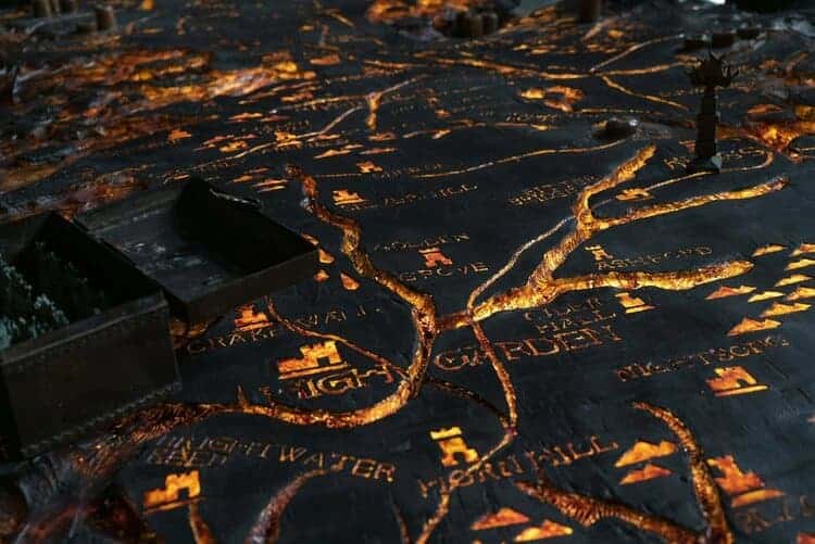 The Painted Table shaped in the map of Westeros is alight from candles beneath it, glowing to show the rivers and mountains of Westeros.