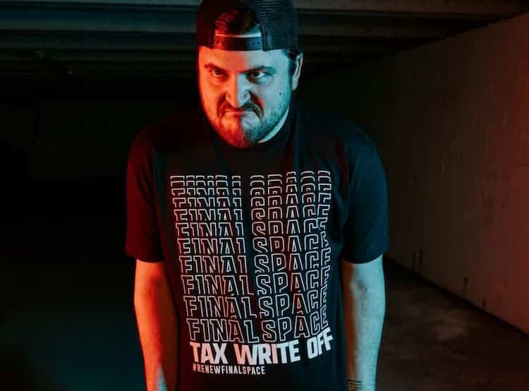 Olan Rogers frowning while wearing a T-shirt that reads "Final Space" several times, then "Tax Write Off" and #RenewFinalSpace.