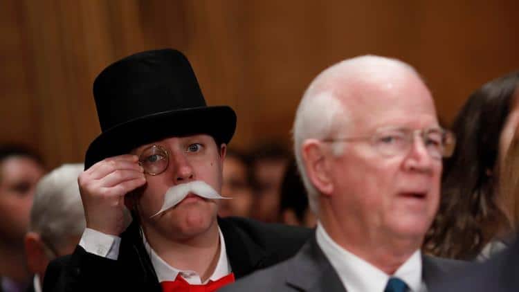 Man dressed as Pennybags at a Senate hearing