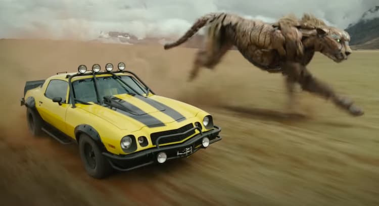 Cheetor, in cheetah-inspired beast form, runs alongside Bumblebee, who is driving in car form.