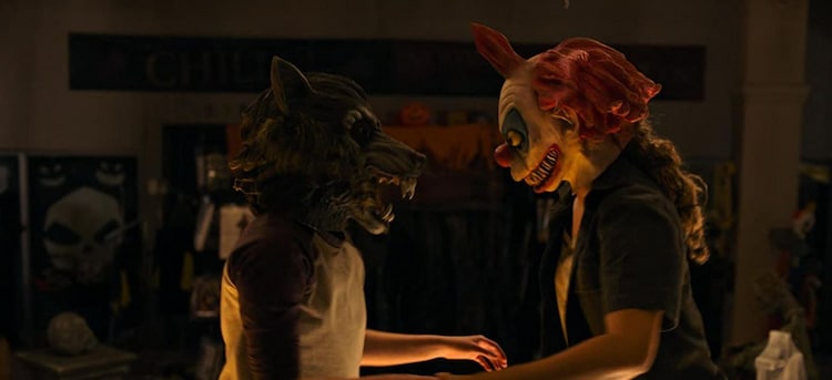 Ellie dances wearing a werewolf mask, Riley in a Killer Clown mask
