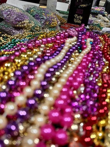 Colorful strands of beads lined up next to a Nerdi Gras program guide.