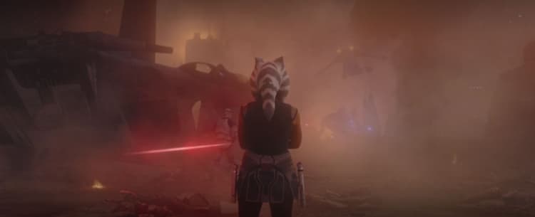 A young Ahsoka surveys the battlefield of Mandalore with her arms crossed as a laser bolt whizzes by her left.