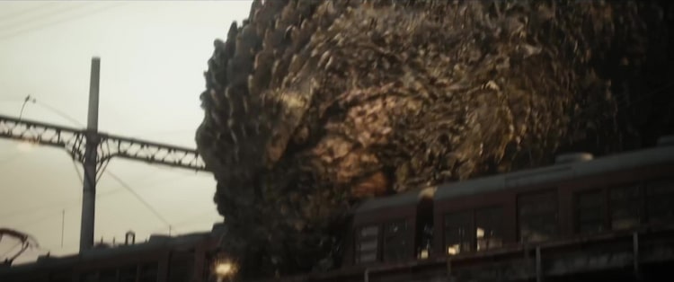 Godzilla biting down on a train car.