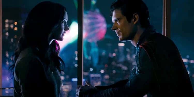 Lois and Superman are sitting across from each other in Superman's apartment. A giant glowing alien is outside the window. It's floating above the city. Green Lantern is fighting the alien. Superman and Lois are looking at each other.