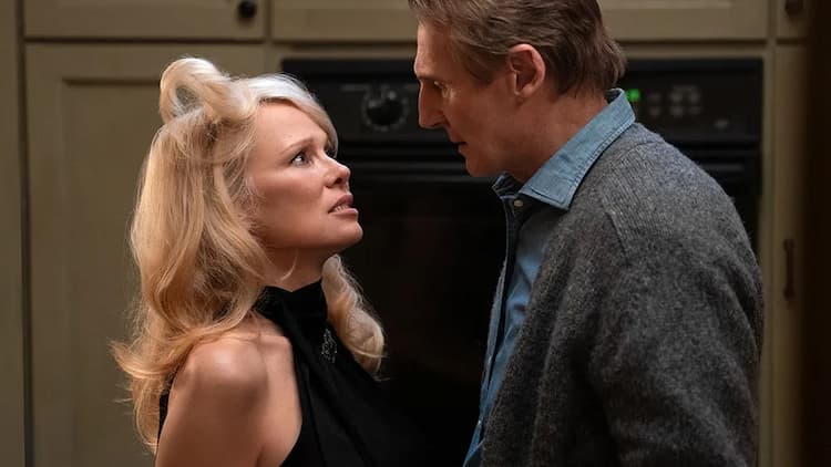 Beth and Frank are in the kitchen. They are looking into each other's eyes. Beth's hair is flicked upwards. They are standing in front of an oven.